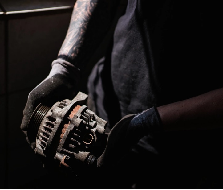 Mechanic holding in his hands a old a worn Clark forklift alternator