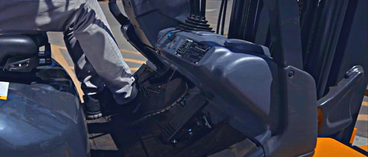 Lift truck drive pushing the brake pedal of a Komatsu forklift to test its master cylinder.