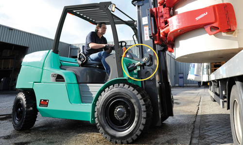 Lift truck operator using a Mitsubishi forklift to unload a load from a truck. The Mitsubishi forklift tilt cylinder it's highlighted with a yellow circle.