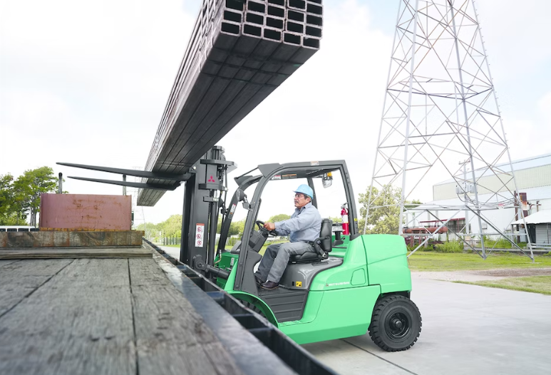 Operator using a Mitsubishi forklift to easily lift heavy loads. The forklift uses a reliable Mitsubishi hydraulic pump to perform this task